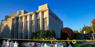 Synagogue exterior with memorial flowers and star-shaped tributes on lawn