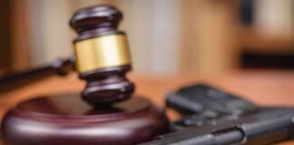 Gavel beside a handgun on a wooden table