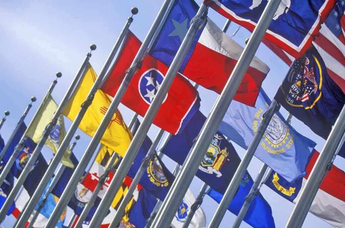 shutterstock_139254692 A row of various flags waving in the wind against a clear blue sky