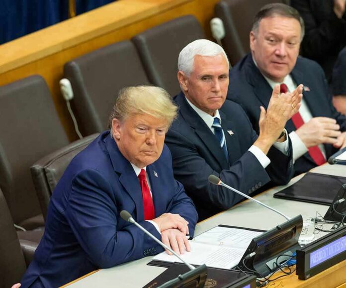 three men in suits seated at a conference table
