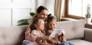 Woman reading a book with two young girls on a sofa