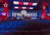 Debate stage with red and blue lighting and empty audience seats