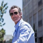 man in sunglasses wearing a light blue shirt outdoors
