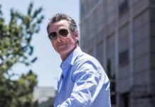 man in sunglasses wearing a light blue shirt outdoors