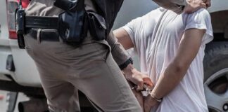 police officer handcuffing a person beside a vehicle
