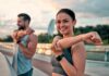 Woman stretching her arm outdoors with man in background