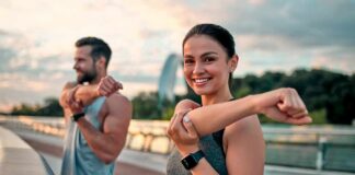 Woman stretching her arm outdoors with man in background