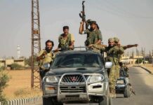 armed men riding on pickup trucks in a convoy