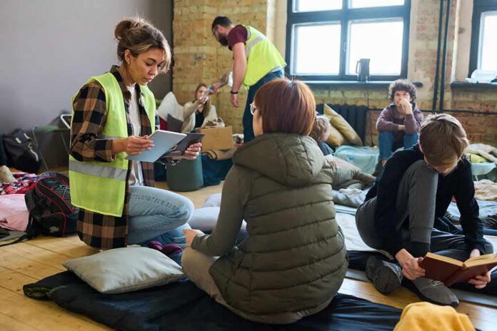 Volunteers assist people resting on mats in a temporary shelter