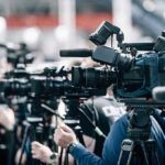 ESPN Panel ERUPTS After NBA Star Switches Gender Broadcast cameras on tripods at a press event