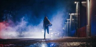 Person running at night near police car with flashing lights
