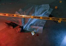 crime scene body under sheet behind caution tape