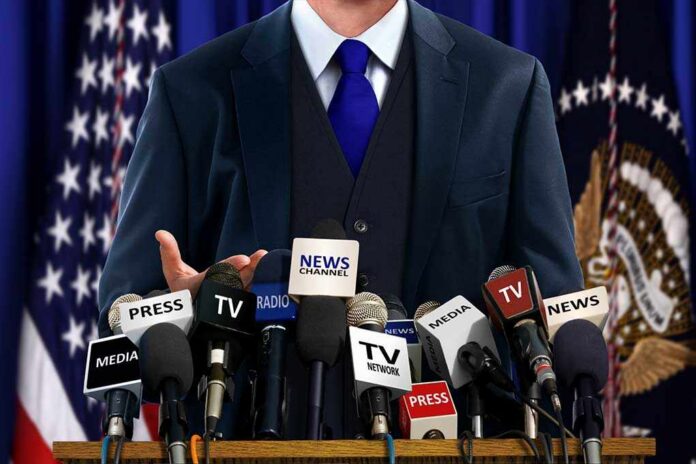 A speaker at a press conference with multiple microphones in front of them