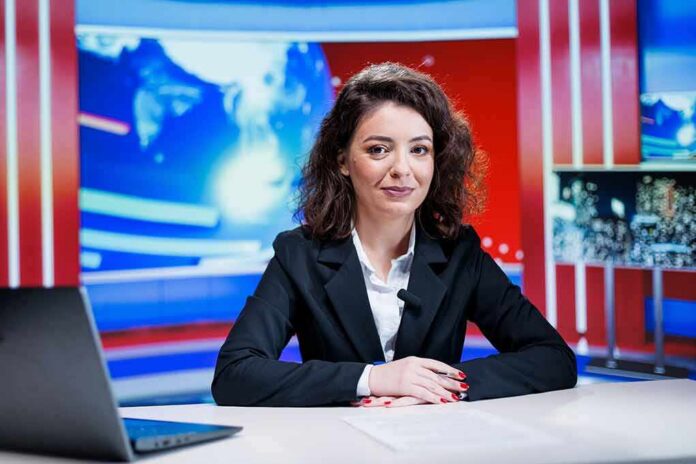 shutterstock_2550477051 News anchor seated at a broadcast desk