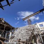 Collapsed industrial building with exposed beams under a blue sky