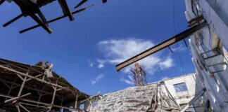 Collapsed industrial building with exposed beams under a blue sky