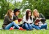 Group of young women reading books on grass in a park