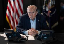 White House Humiliated as ‘Trump TV’ FLOPS Donald Trump seated at a table between two desk phones
