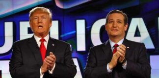 two men in suits clapping on a brightly lit stage