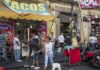 Street taco stand with people and a religious statue on a sidewalk