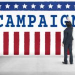 Dem Darling Rocked By ANOTHER Rape Scandal Man in suit writing on large campaign banner with stars and stripes