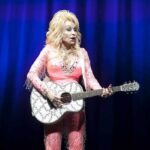 Dolly Parton’s Final Moments Stir Questions Singer in pink outfit playing a glittery acoustic guitar on stage