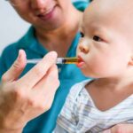 Surrogate Sued For NOT Aborting Baby Baby taking liquid medicine from an oral syringe held by an adult