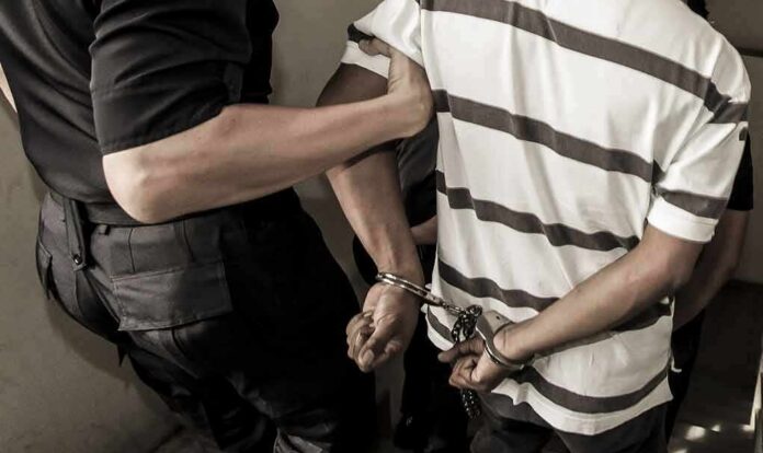 person in handcuffs escorted by an officer