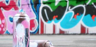 spray paint cans on pavement in front of a graffiti wall