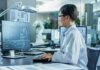 Engineer in lab coat working at a computer in a modern lab