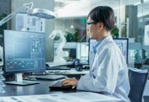 Engineer in lab coat working at a computer in a modern lab