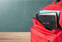 Red backpack with books on a classroom desk