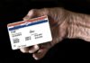 Elderly hand holding a health insurance card