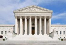 Front view of the Supreme Court building with large columns and steps under a blue sky
