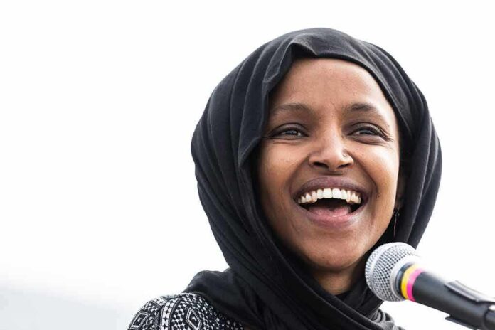Ilhan Omar smiling while speaking at a microphone