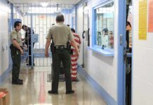 Desperate Manhunt Underway – Convicted Killer Escapes! Corrections officers escort an inmate in a jail hallway
