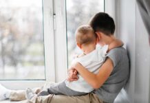 two children hugging by a window