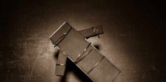 Cardboard figure bound with rubber bands on a dark surface