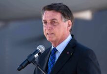man in suit speaking at a microphone