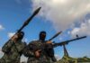 Armed militants in camouflage with rocket launchers and a machine gun