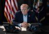 Donald Trump seated at a table between two desk phones