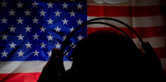 Silhouette with headphones against American flag background.