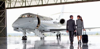 Two businesspeople walking towards a private jet in hangar.