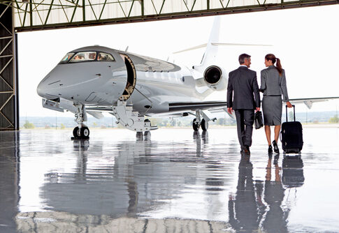 Two businesspeople walking towards a private jet in hangar.
