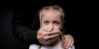 Man covering young girl's mouth with hand.