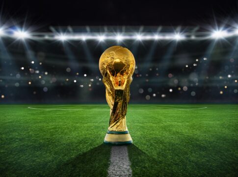 Golden trophy on soccer field under stadium lights