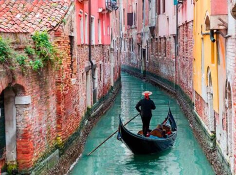 A gondola navigating through a narrow Venetian canal surrounded by historic brick buildings
