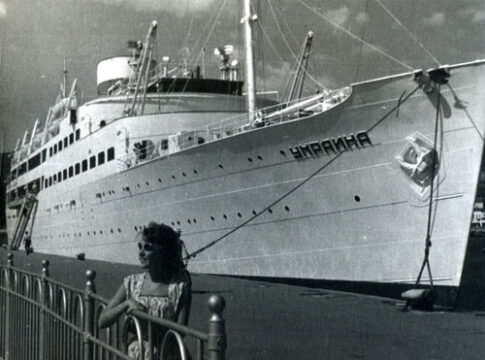 A large ship named Ukraine docked at a pier.