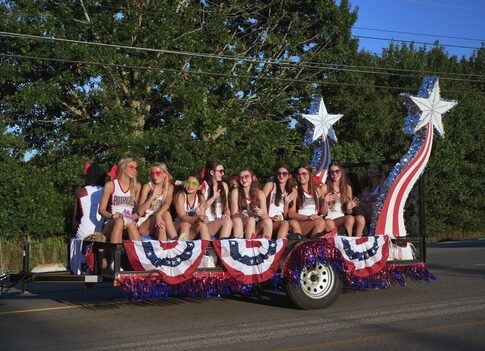 A group of young women on a decorated parade float celebrating a patriotic event