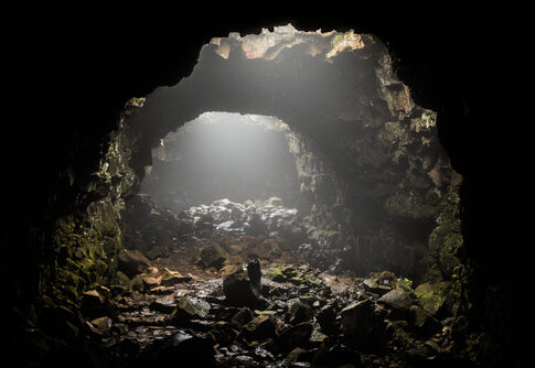 Interior of a cave with light streaming through openings and rocky ground